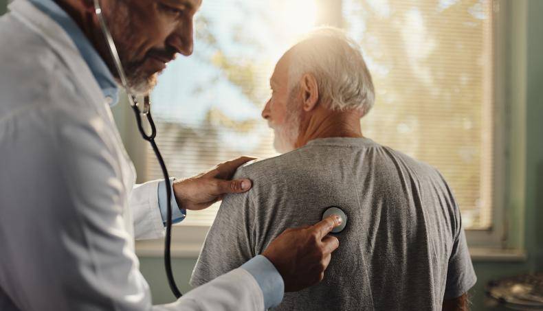 A senior patient is getting their breath checked by a physician 