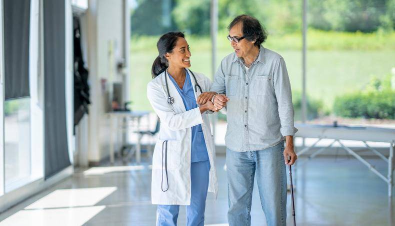 A physician walking alongside a senior arms intwined as they discuss treatment.
