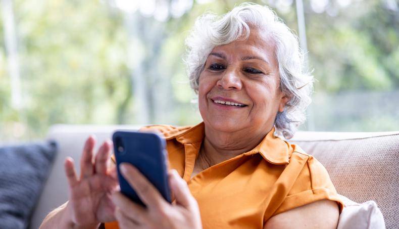 Senior sitting on a couch looking at their smart phone