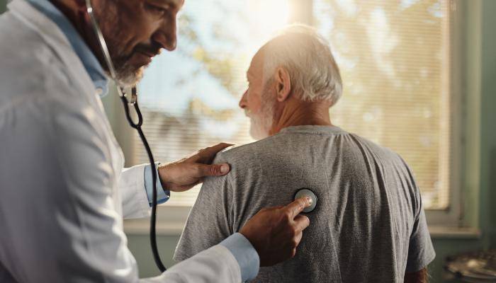A senior patient is getting their breath checked by a physician 