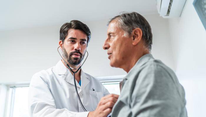 Doctor intently listening to patient heart with stethoscope