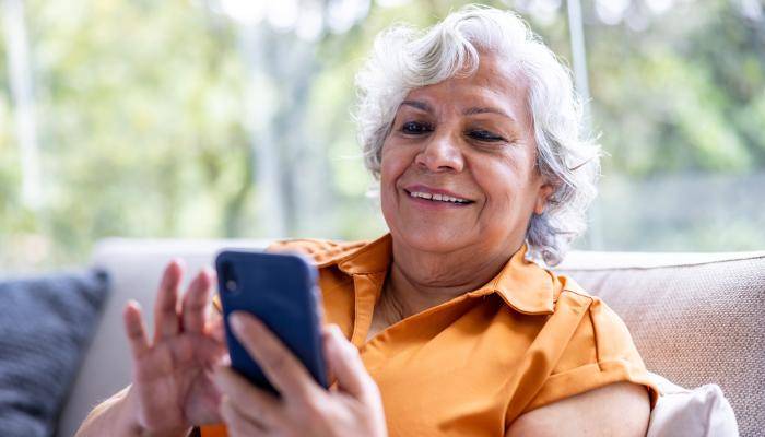 Senior sitting on a couch looking at their smart phone