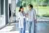 A physician walking alongside a senior arms intwined as they discuss treatment.